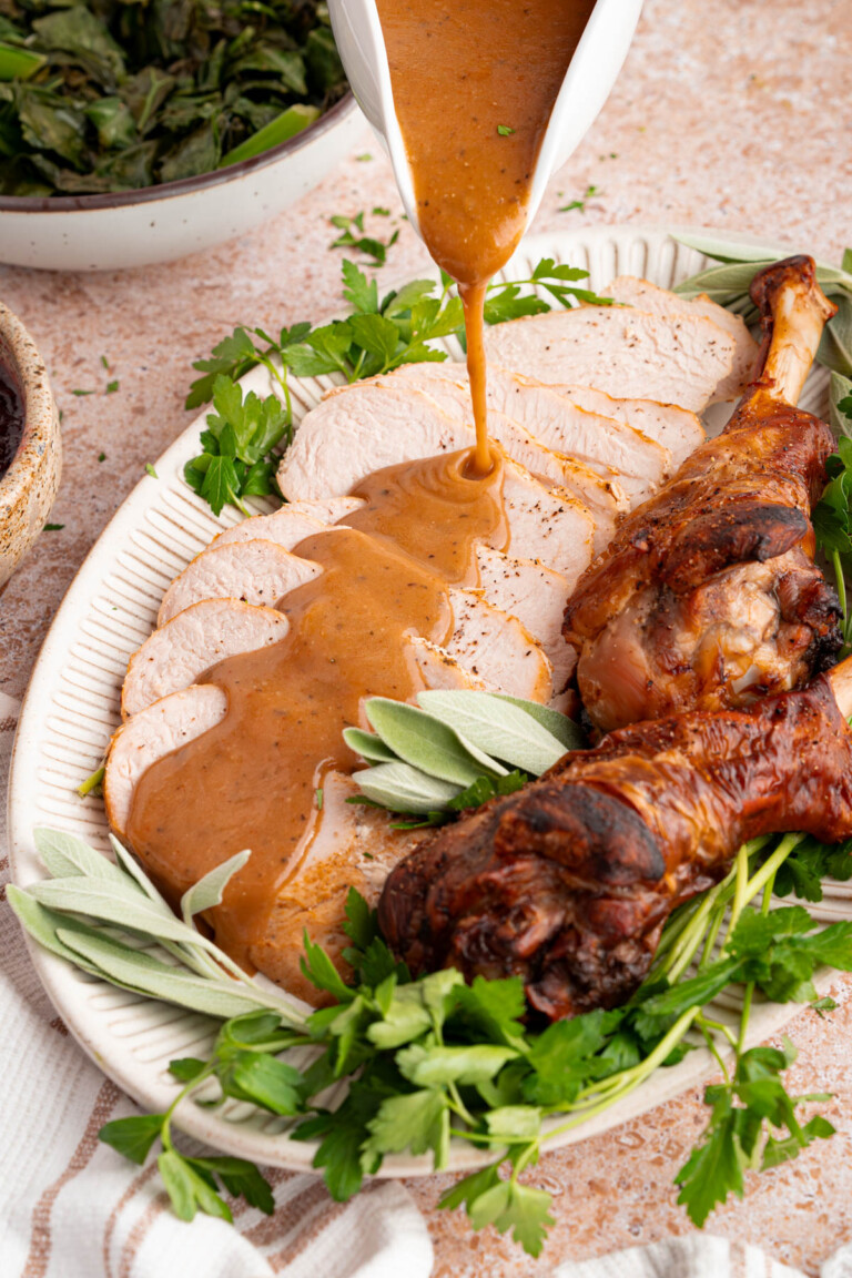 Turkey gravy from drippings is poured over sliced turkey breast for serving.