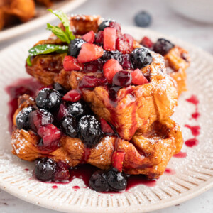 Two pieces of waffles with berry compote and powdered sugar on top.