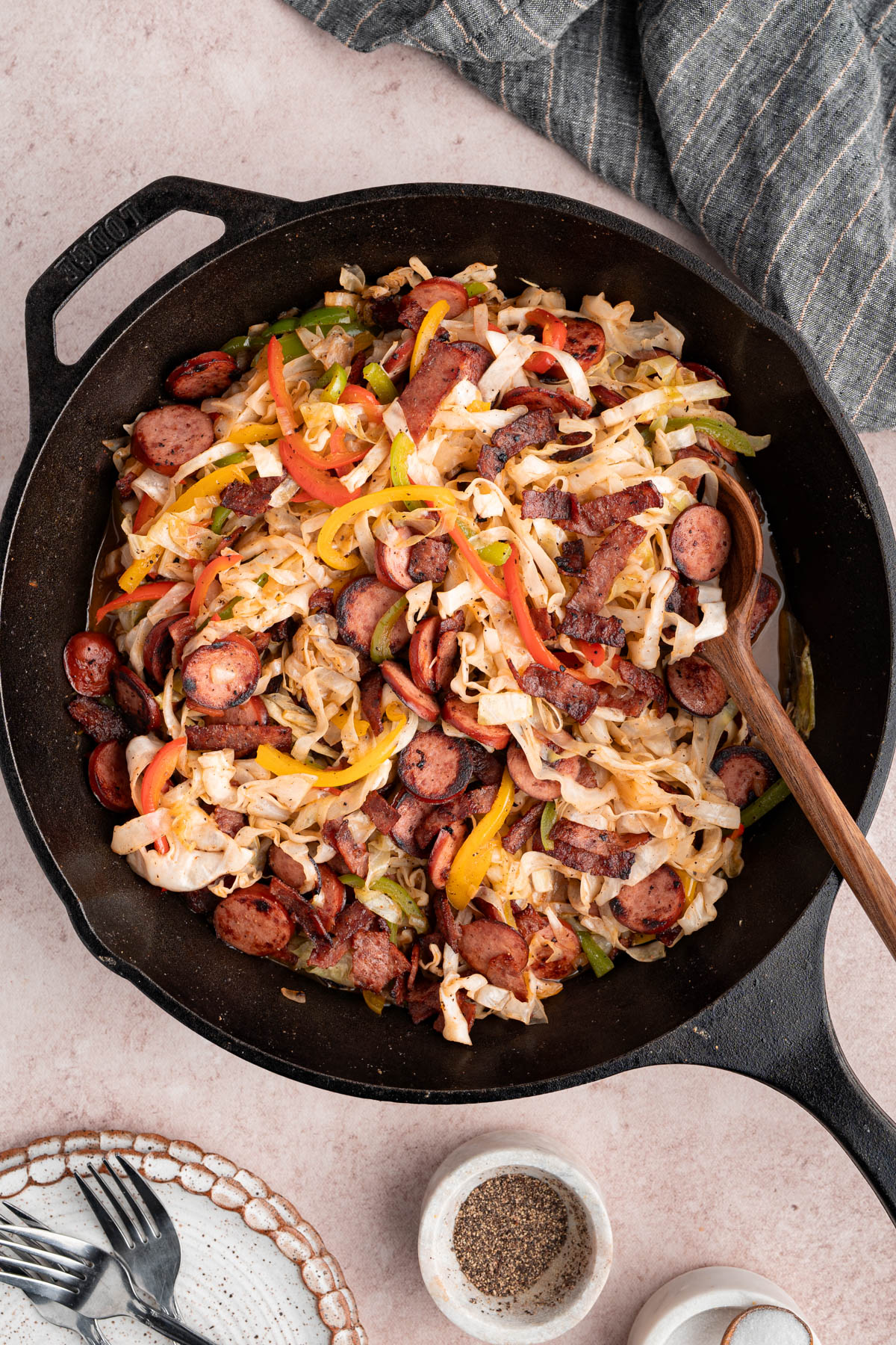 The cooked southern fried cabbage in a cast iron skillet with a wooden spoon for serving.