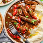 Pepper steak with potatoes on a plate on a countertop.