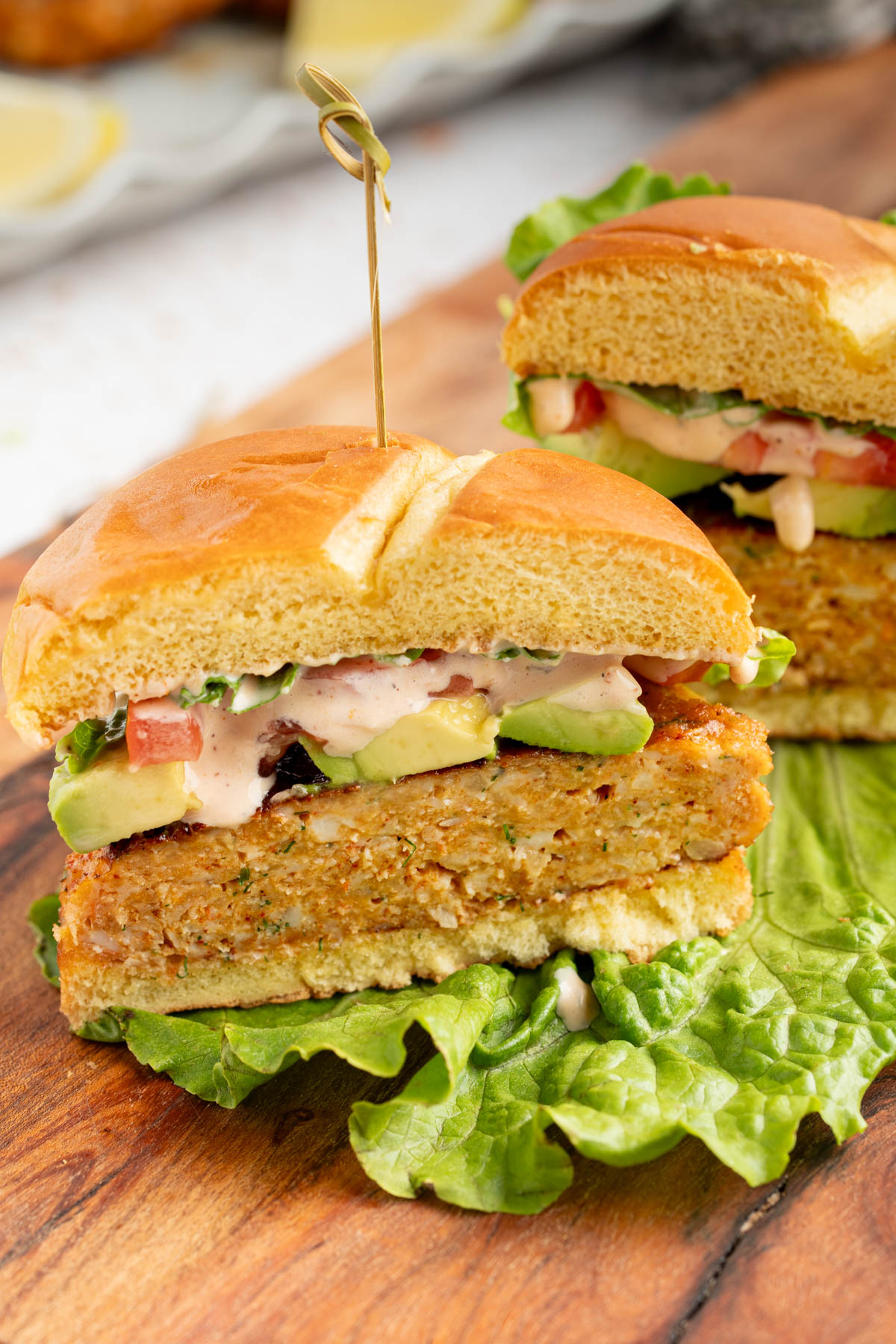 The shrimp burger sliced in half on a wooden cutting board.