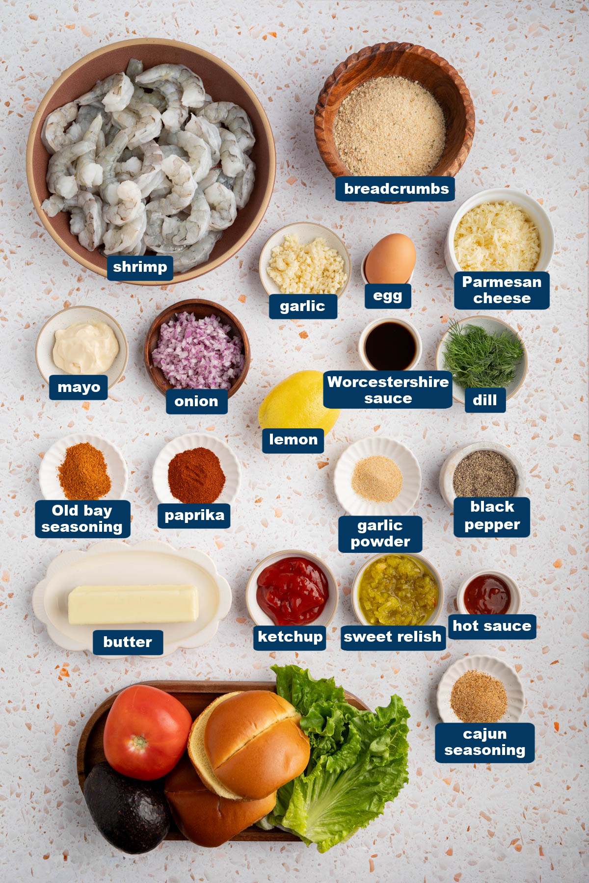 All of the ingredients for shrimp burgers in bowls on a white countertop.