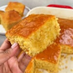 A close up photo of a slice of honey butter cornbread with honey butter drizzled on top