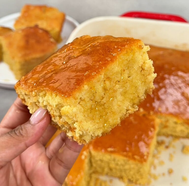 A close up photo of a slice of honey butter cornbread with honey butter drizzled on top