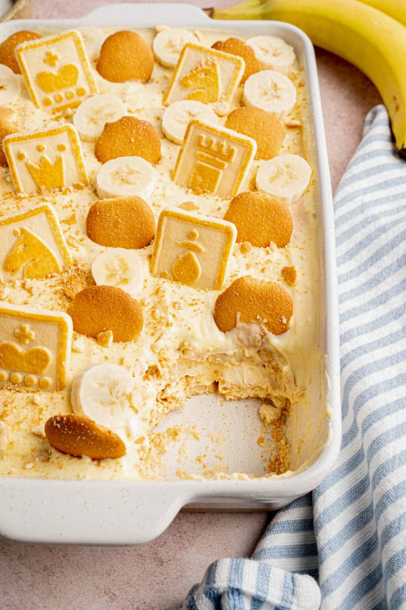 Homemade banana pudding in a white baking dish with a piece taken out after eating.