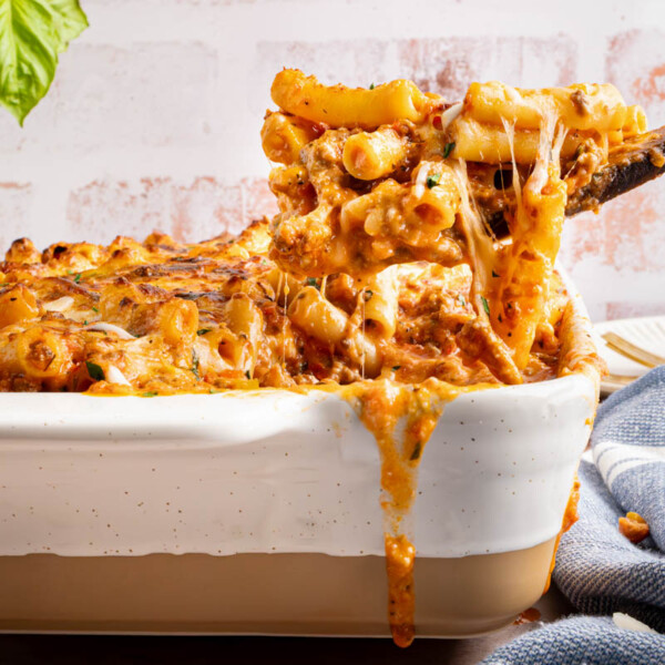 A spoon scooping the baked ziti out of the baking dish.
