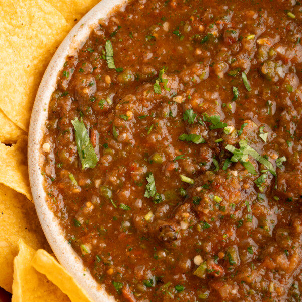 A bowl of restaurant-style salsa with chips on the side.