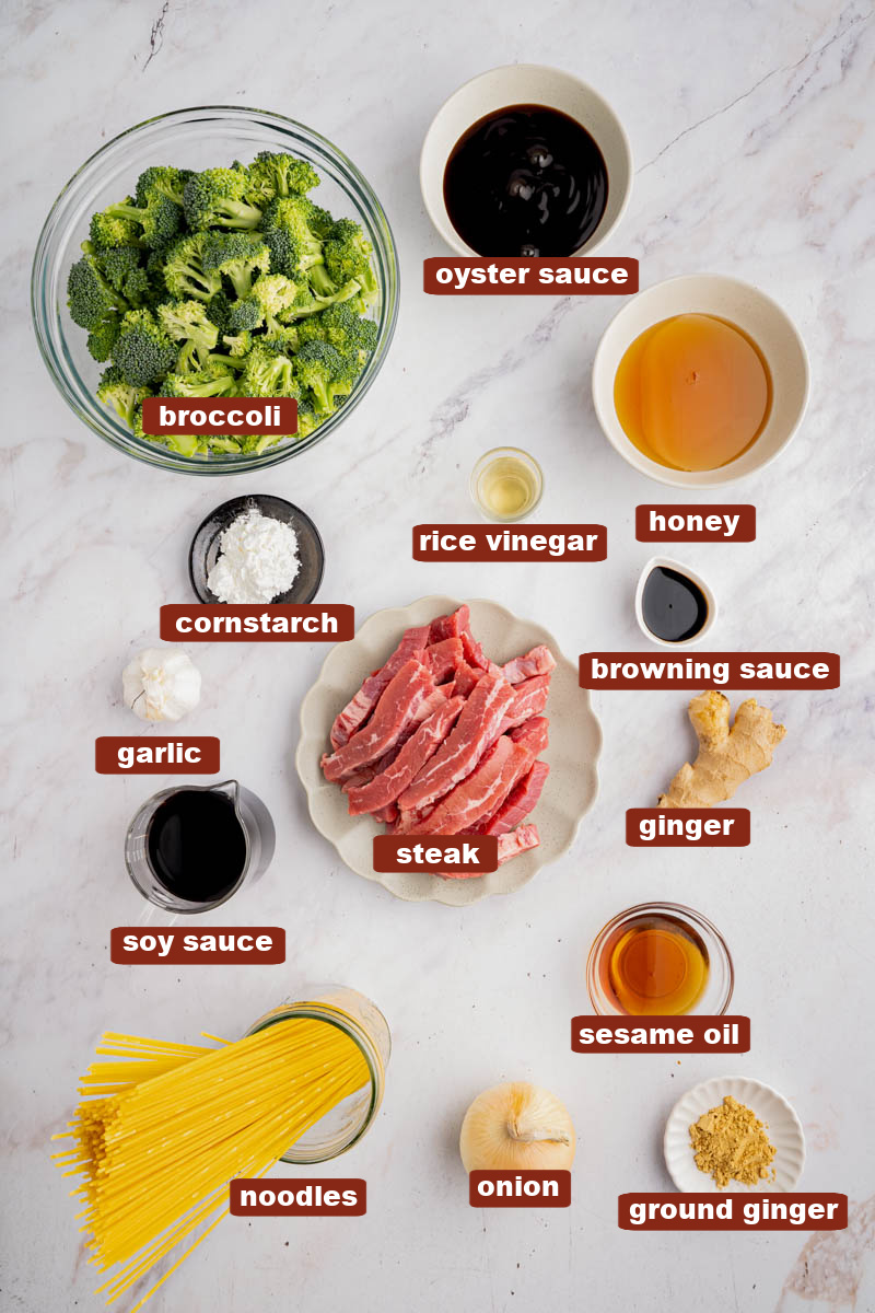 All of the ingredients for beef and broccoli lo mein in bowls on a white countertop.