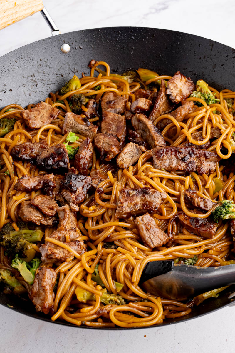 Beef and broccoli lo mein noodles in a wok after cooking.