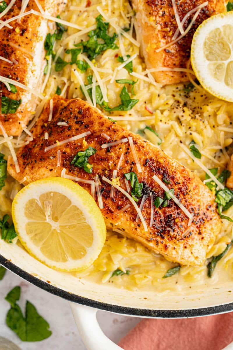 Lemon salmon orzo in a skillet with lemon slices for serving. 