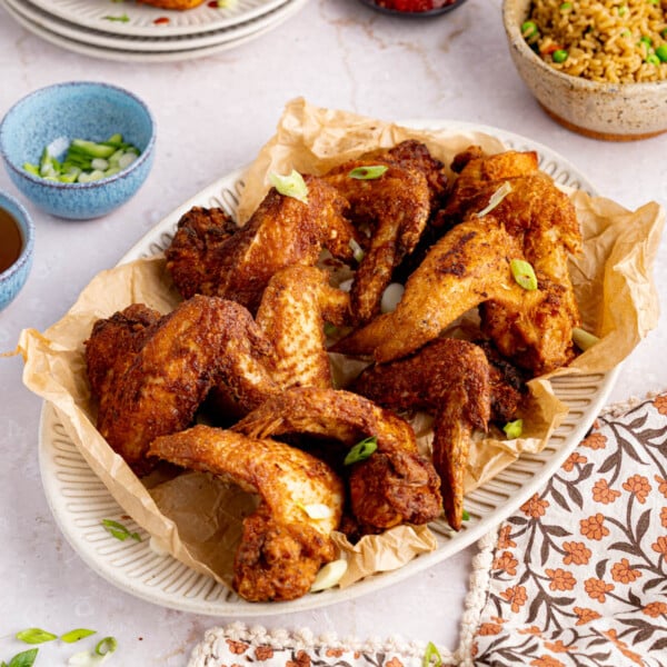A plate of chinese chicken wings sites on a table for serving.