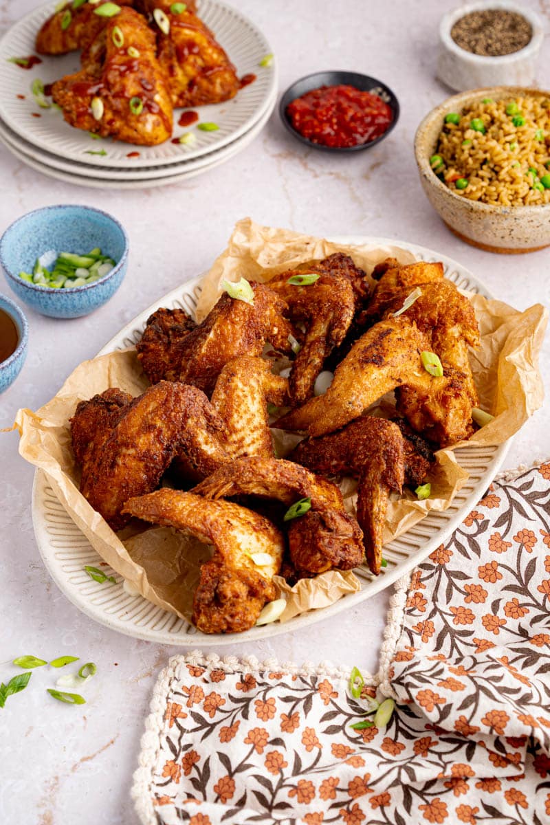 A plate of chinese chicken wings sites on a table for serving.