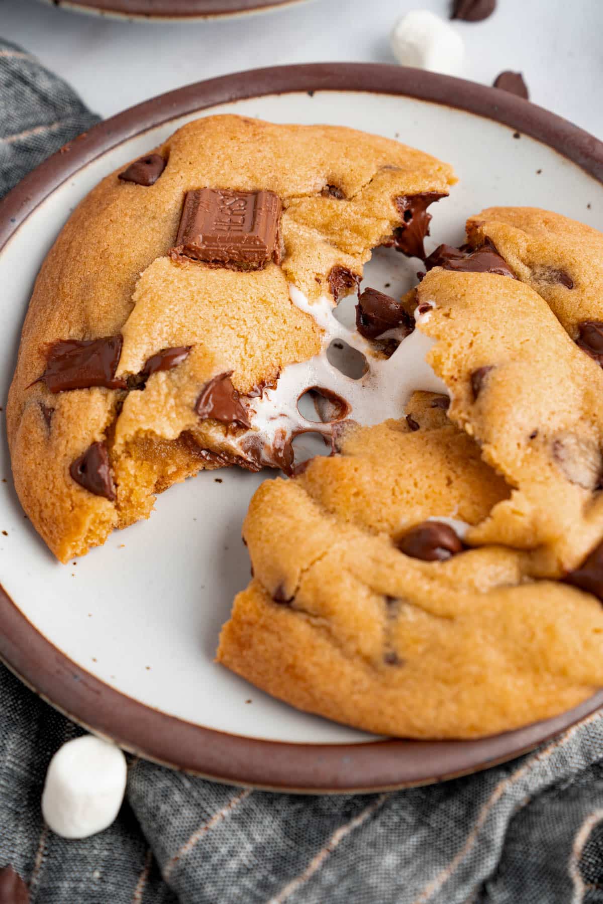 A s’mores cookie that is broken in half sits on a plate for serving.