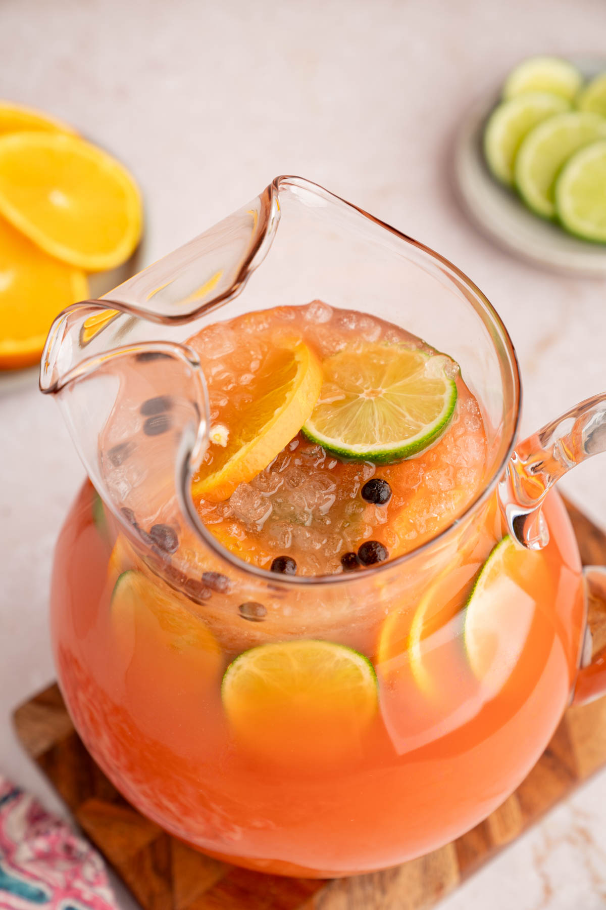 Rum punch in a pitcher sitting on top of a wood cutting board.