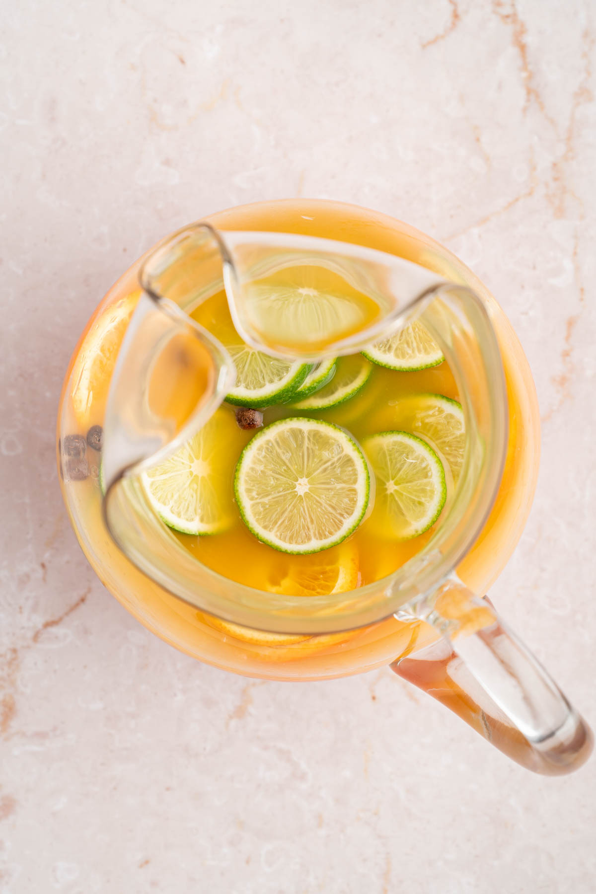 The fresh sliced fruit floating on top of the punch in the pitcher.