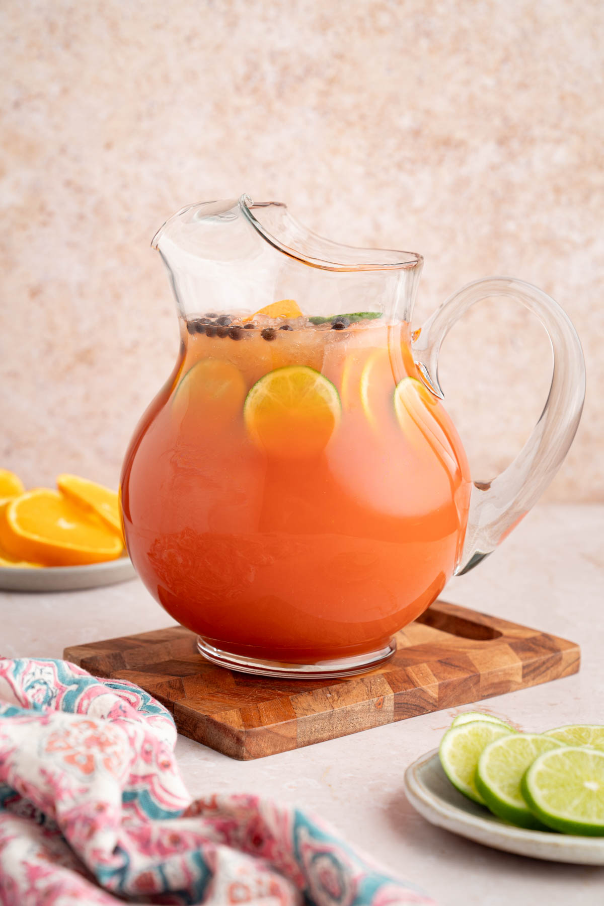Rum punch in a pitcher sitting on a wooden cutting board.