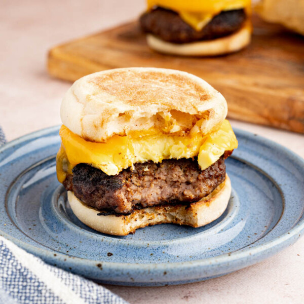 A freezer breakfast sandwich sits on a blue plate on the counter. The sandwich has a bit taken out of it.