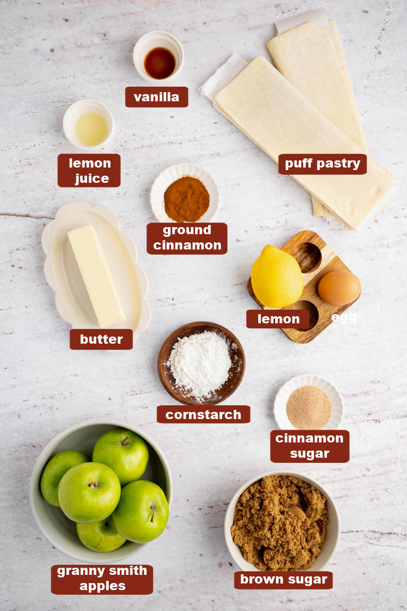 All of the ingredients for apple hand pies in bowls on a white countertop.
