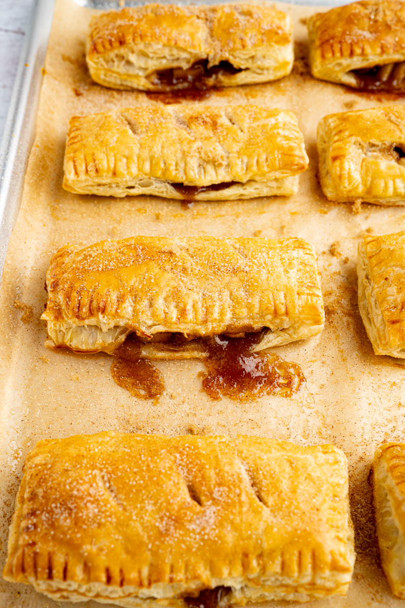 Baked apple hand pies on a baking sheet after coming out of the oven.