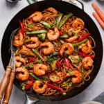Shrimp Lo Mein in a wok with serving utensils for serving.