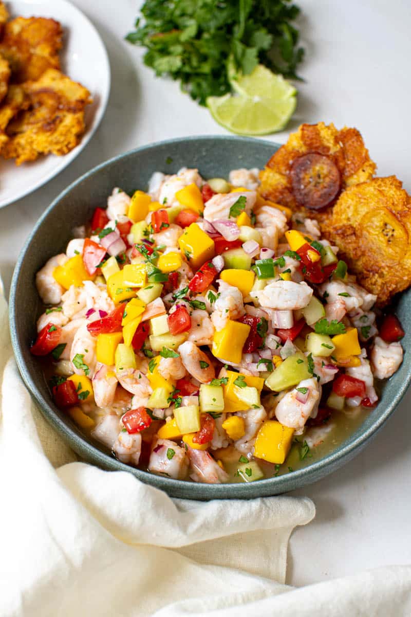 Mango ceviche in a bowl with two plantains on the side of the bowl.
