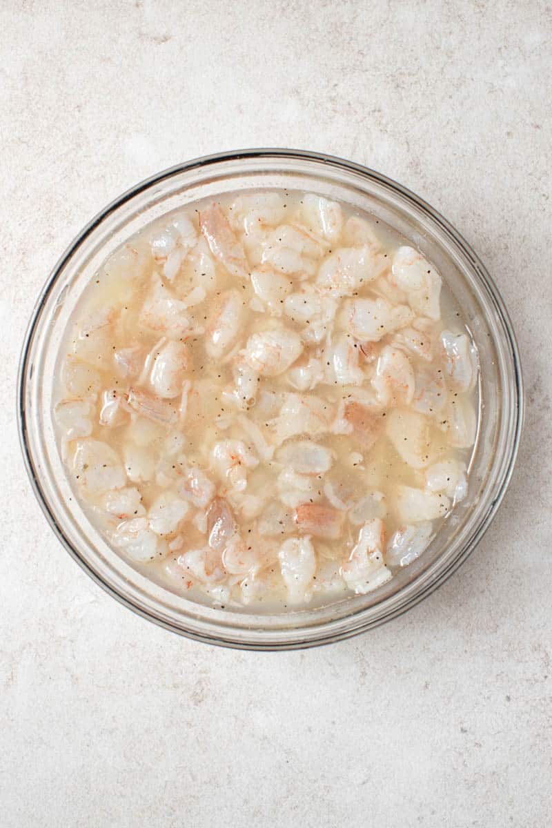 Shrimp marinating in a bowl of freshly squeezed lime juice.