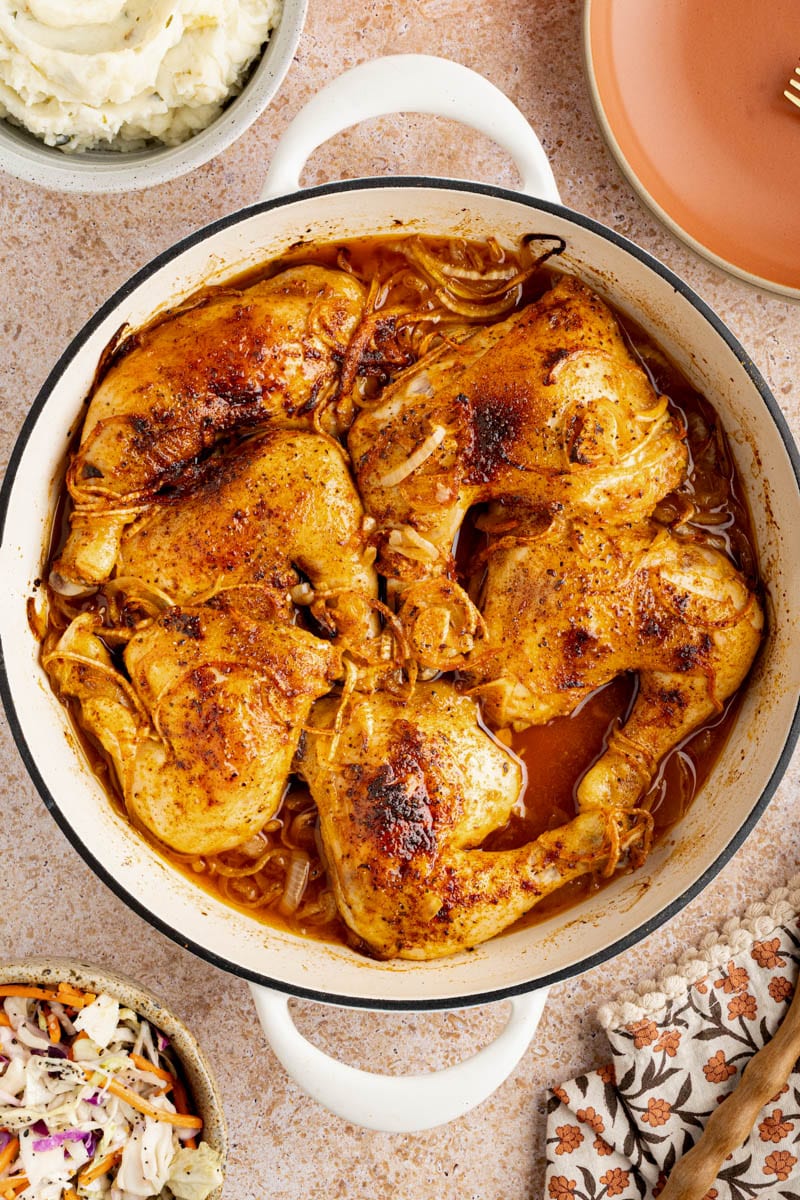 Roasted chicken leg quarters in a roasting dish after roasting in the oven.
