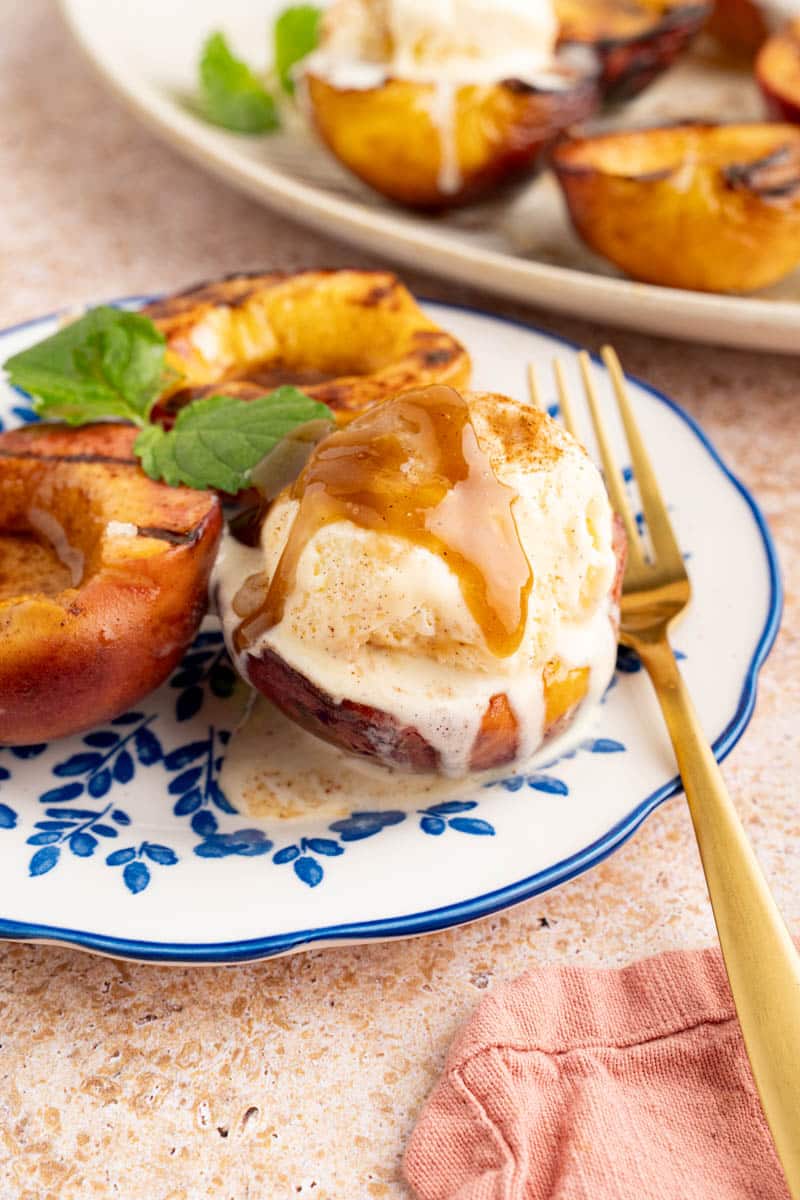 grilled peaches with ice cream on a plate with a fork to the side for serving