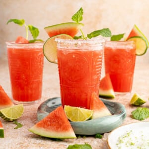 Three glasses of watermelon agua fresca on a countertop for serving.
