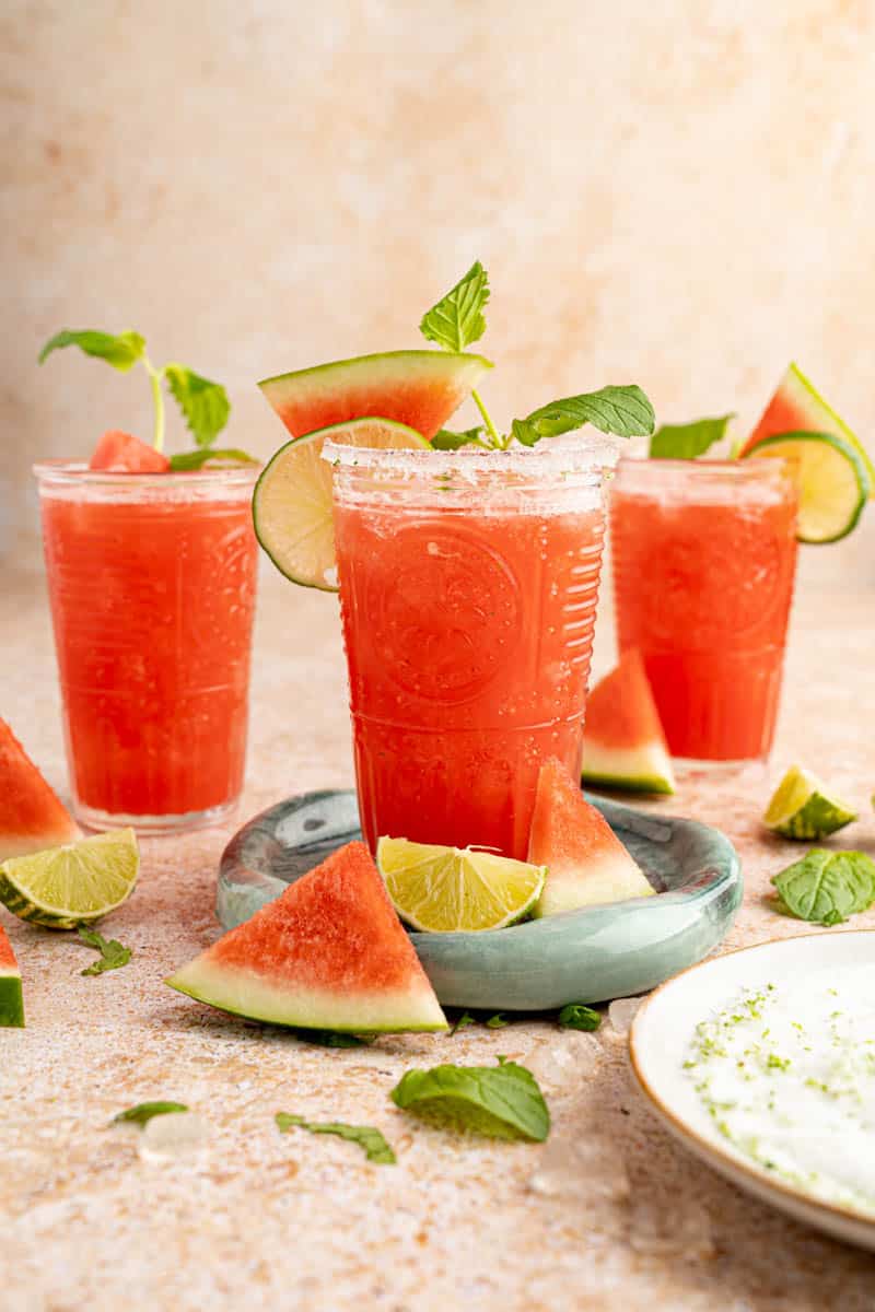 Three glasses of watermelon agua fresca on a countertop for serving.