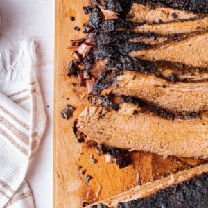 Sliced baked brisket on a wooden cutting board for serving.