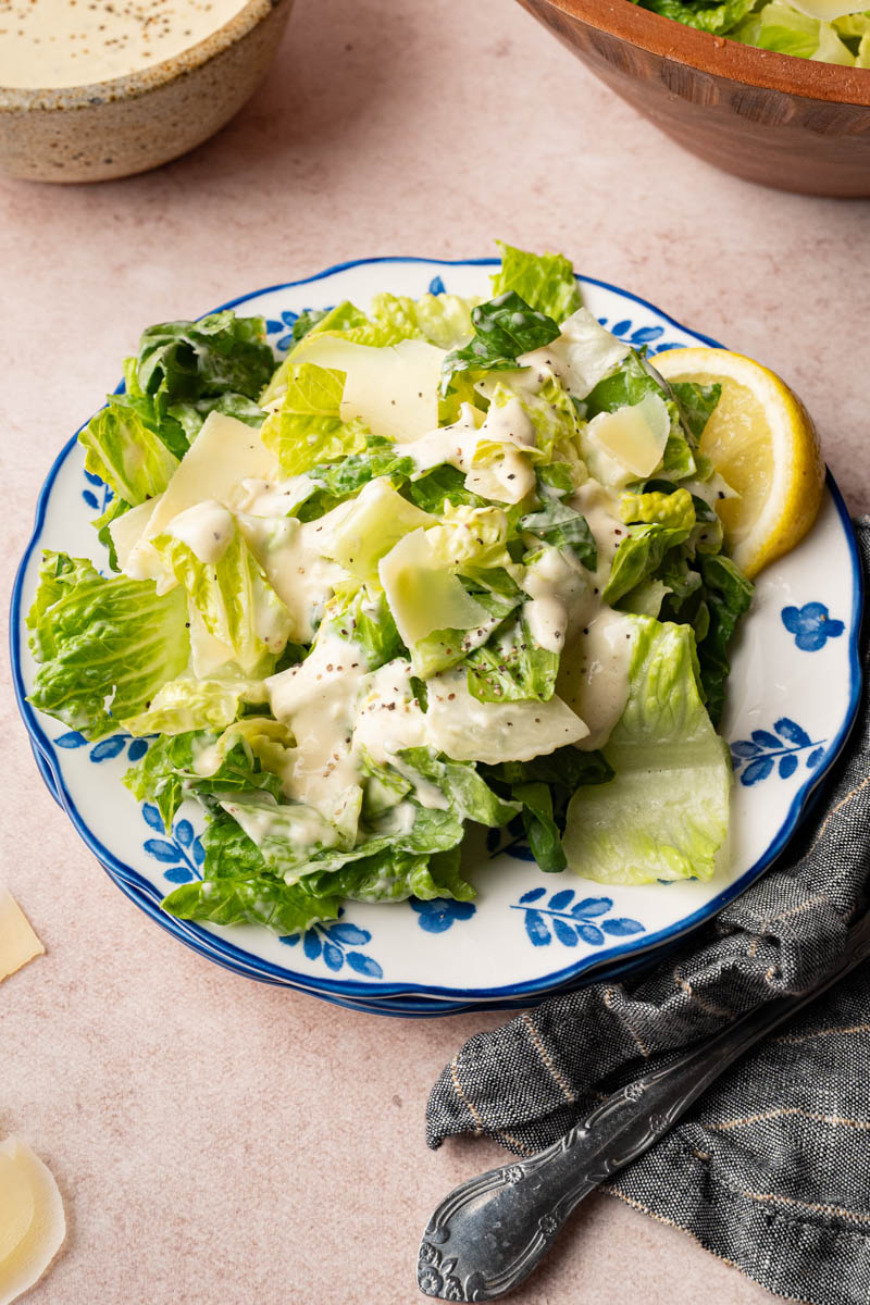 Caesar salad on a plate with a lemon wedge for serving.
