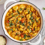 creamy chicken tortellini in a pan before serving. Fresh basil is garnished on top.