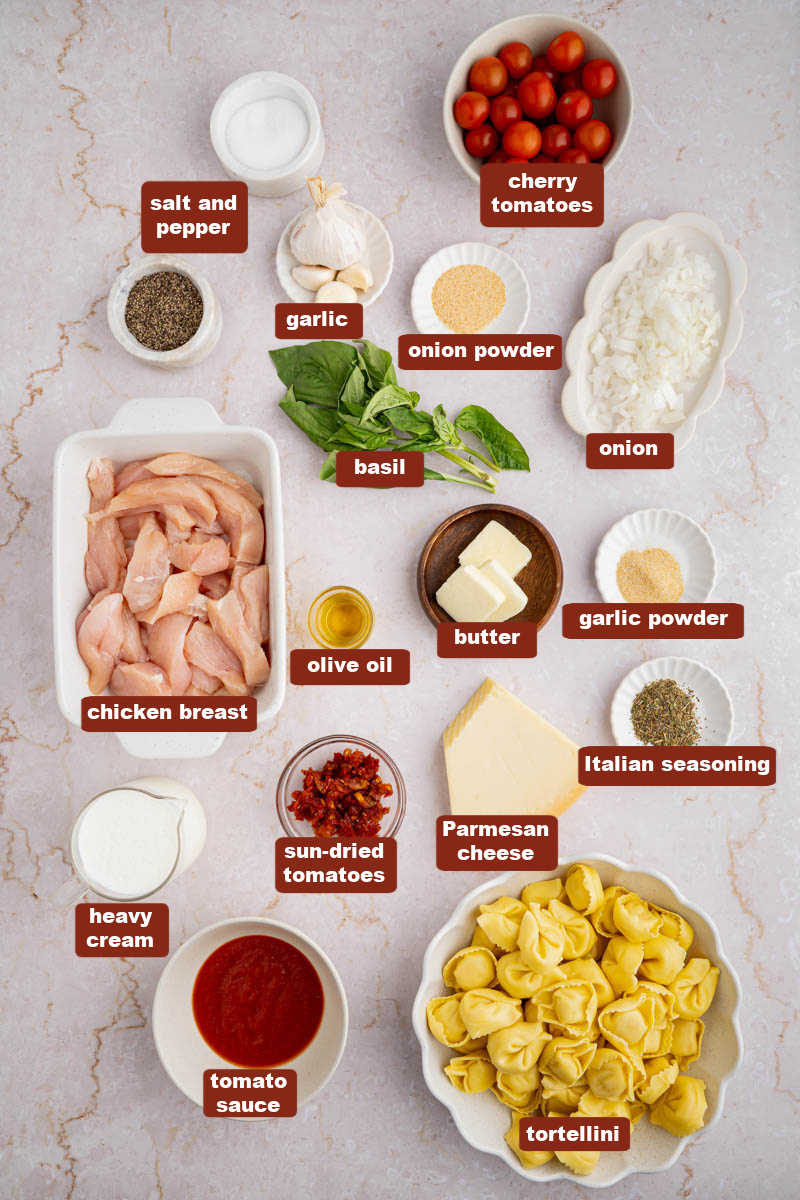 All of the ingredients for creamy chicken tortellini in bowls on a white countertop.