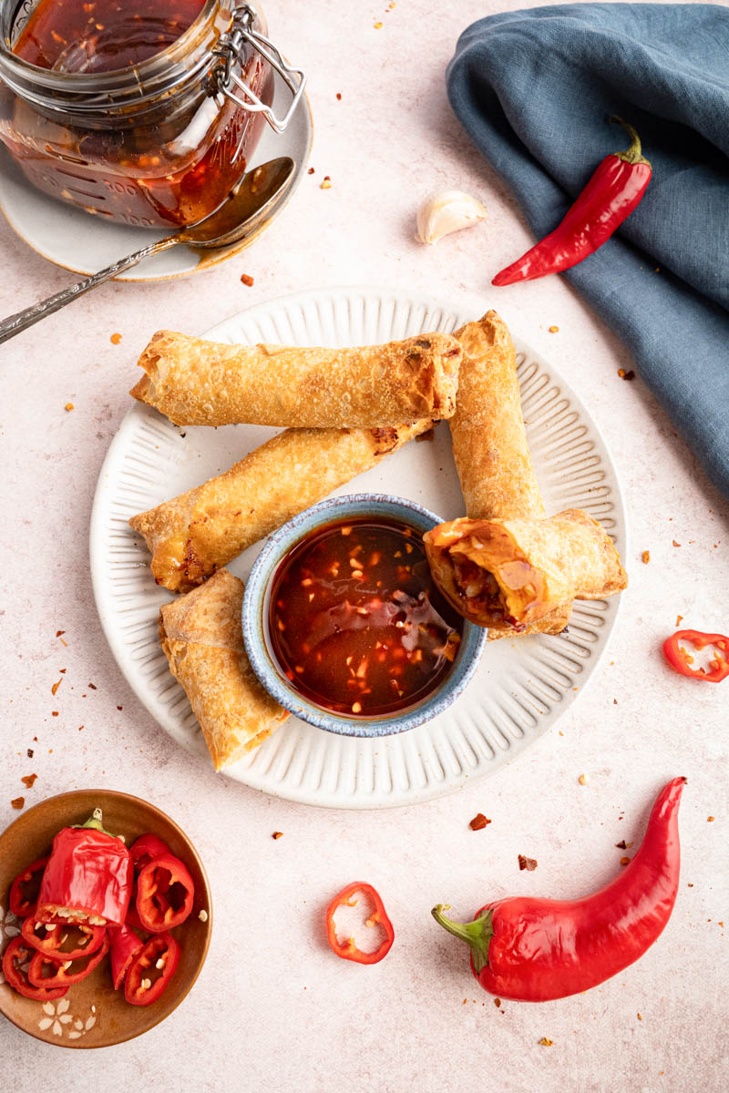 Egg rolls on a plate with a bowl of sweet chili sauce.