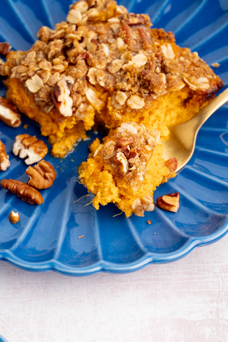 A fork with some of the sweet potato casserole on it sits on a blue plate before serving.