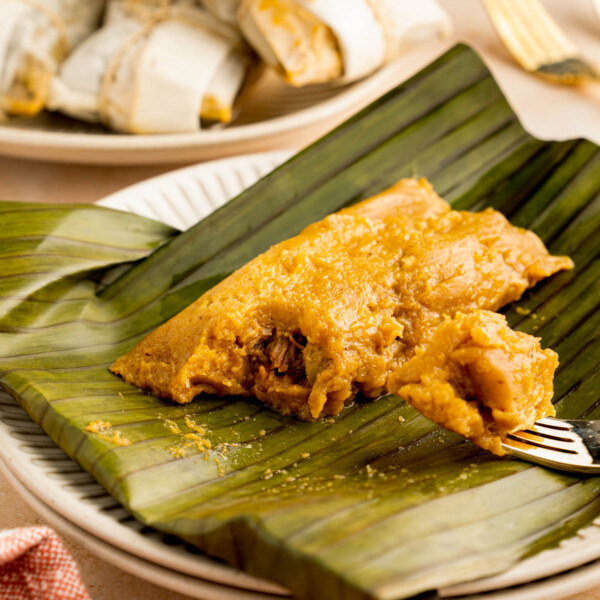 Unwrapped pasteles on a plate with a fork taking a piece out of the pasteles.