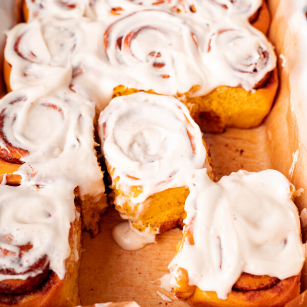 Pumpkin cinnamon rolls in a dish for serving after baking and spreading with cream cheese frosting.