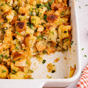 A baking dish with baked seafood stuffing with a scoop removed.