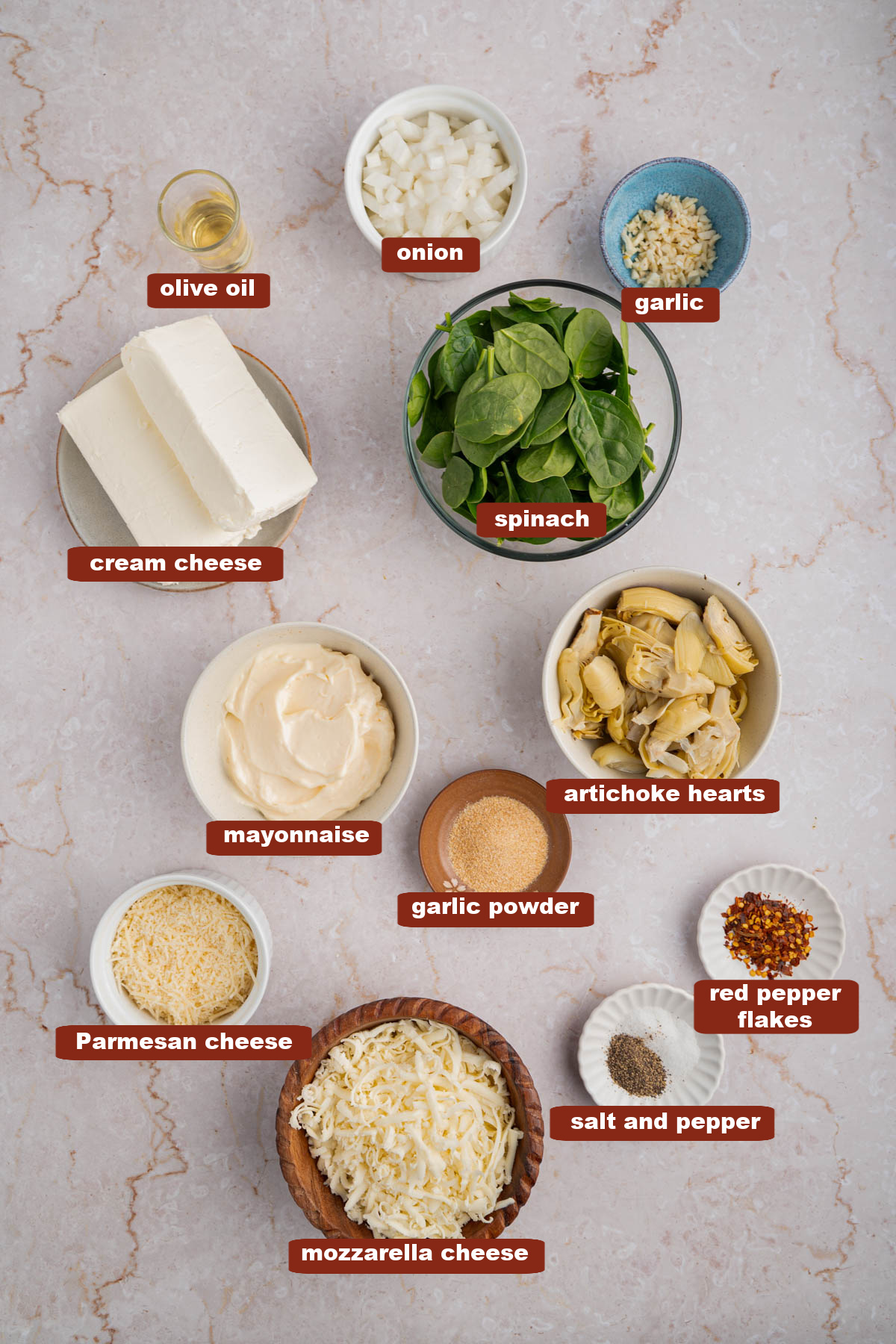 All of the ingredients for spinach and artichoke dip in bowls on a countertop.