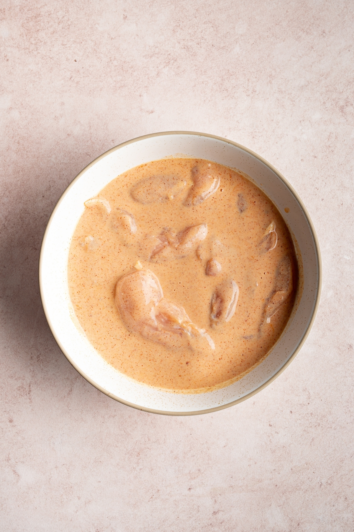 chicken tenders with buttermilk mixed into a bowl
