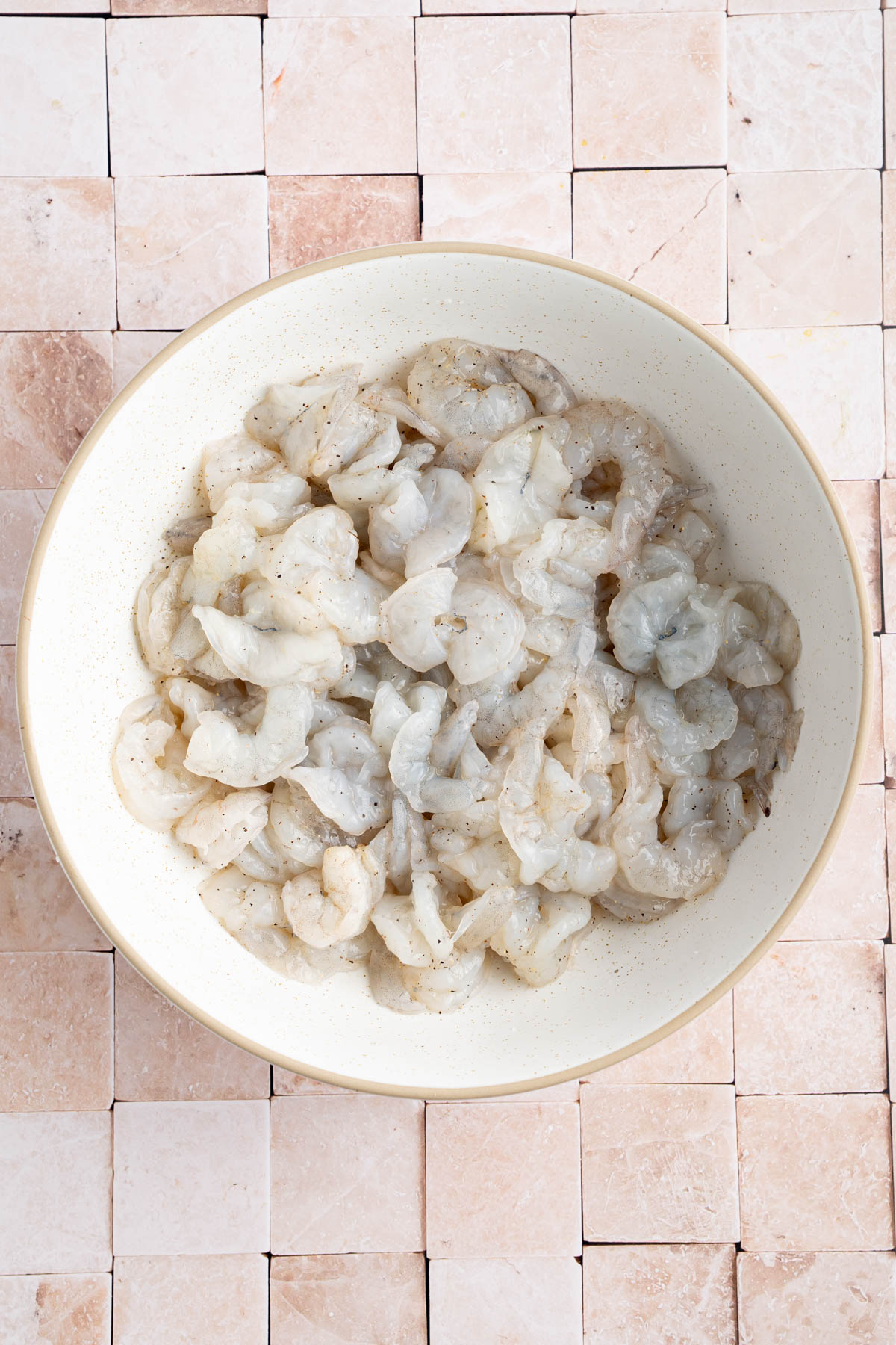 The shrimp in a large bowl with salt and pepper.