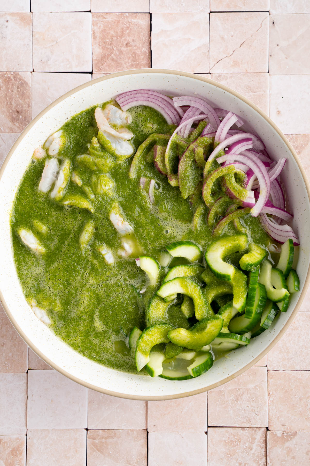 The green sauce in the bowl with the shrimp, red onion, and cucumber.
