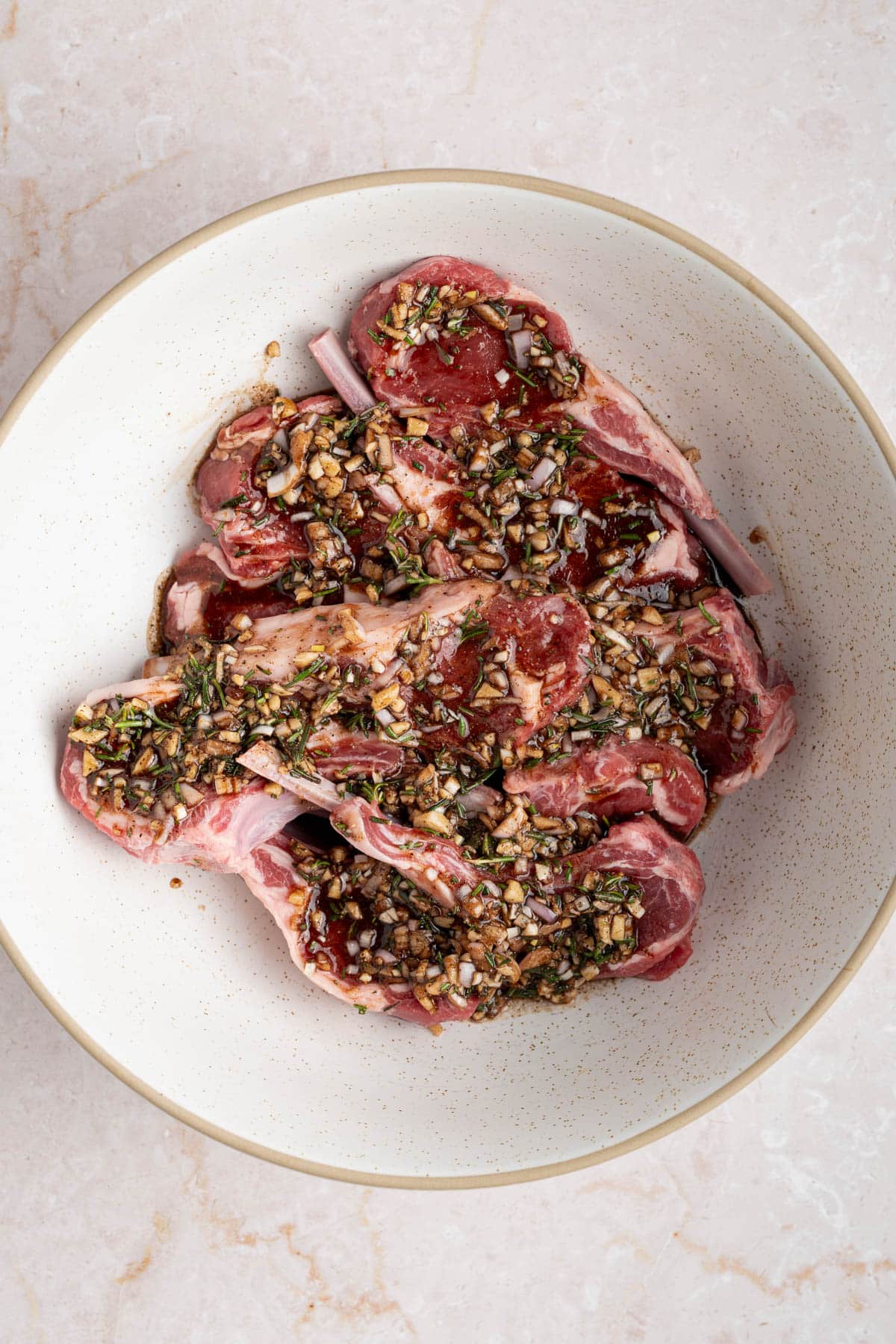 The lamb chops marinating in the bowl covered in the marinade.
