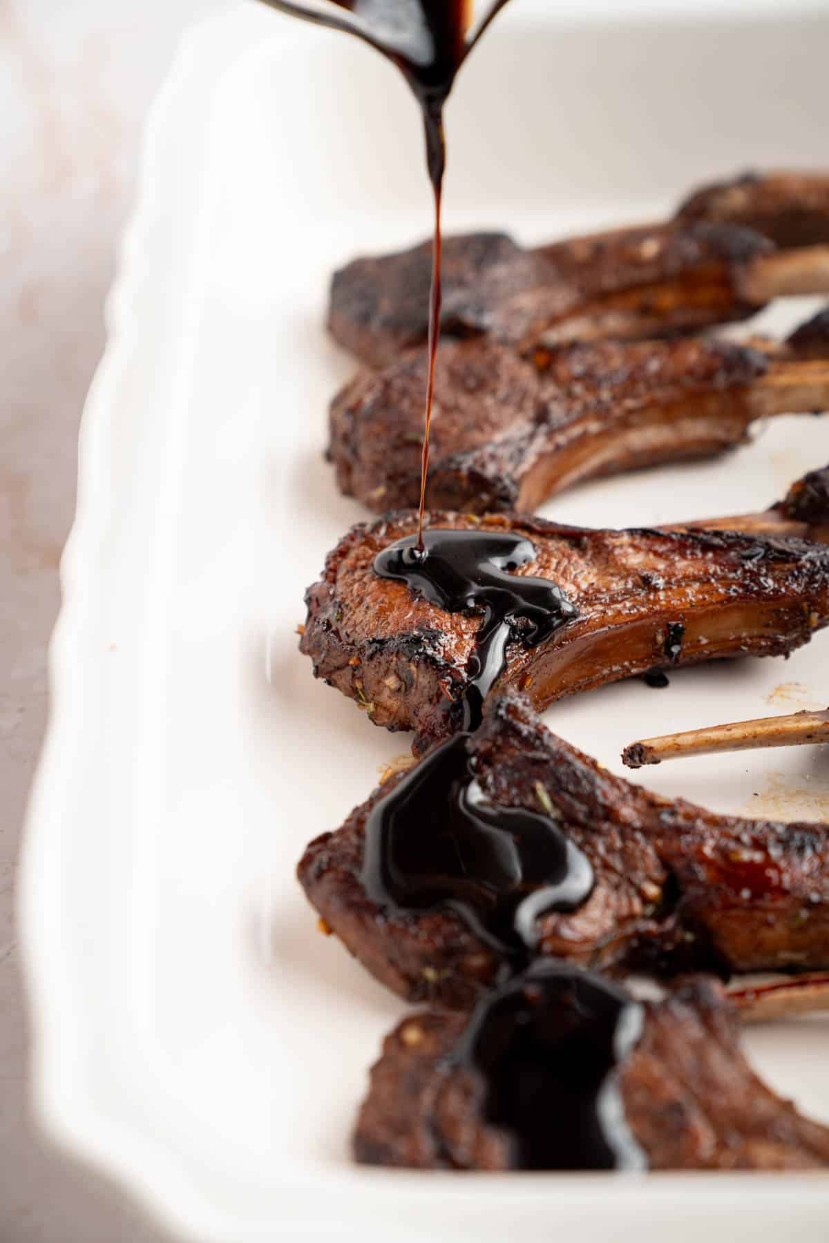 A spoon pours the glaze over the lamb chops before broiling in the oven.
