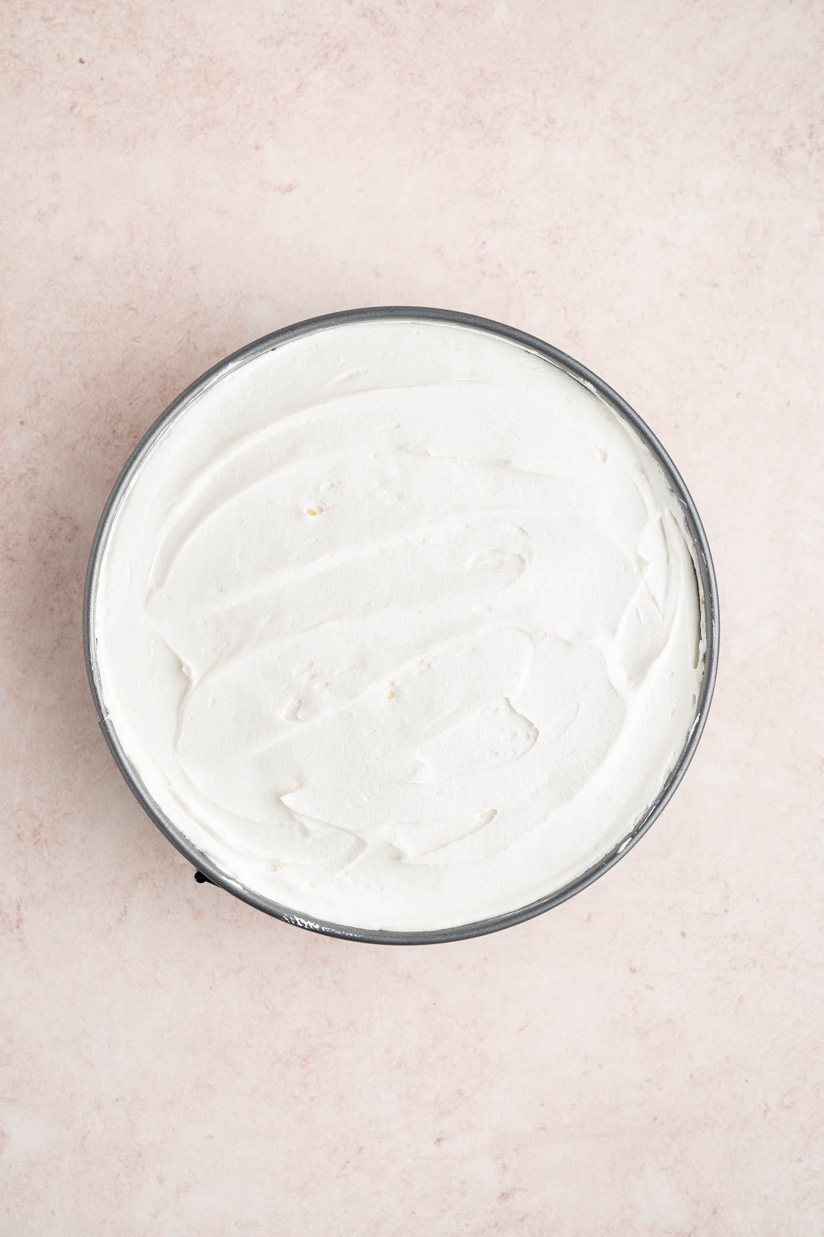 The cool whip spread over the pudding in the pan for the final layer of the cheesecake.