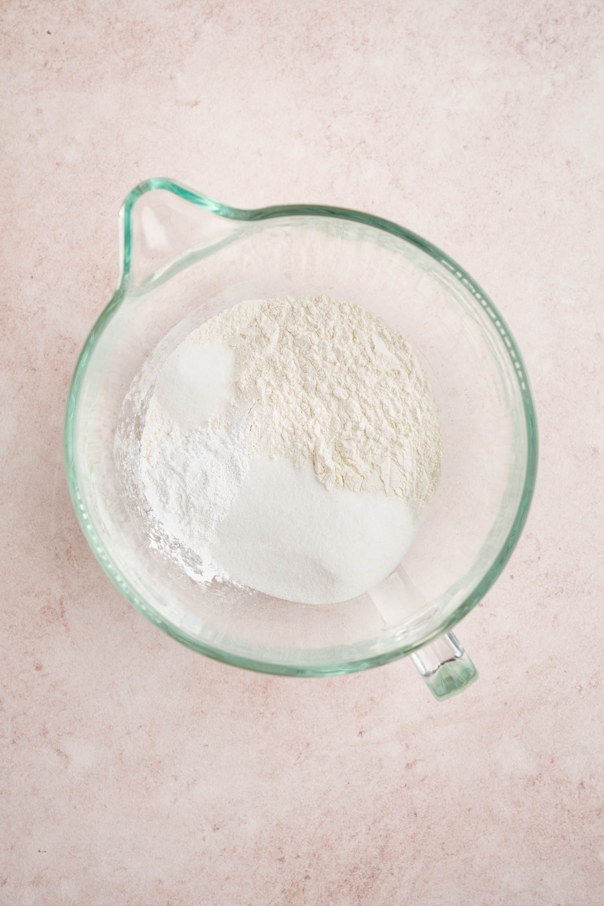 The flour, sugar, baking powder, and salt in a mixing bowl on a countertop.
