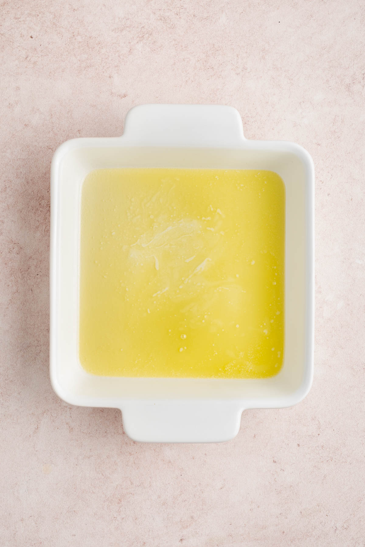 The melted butter in the bottom of the baking dish.