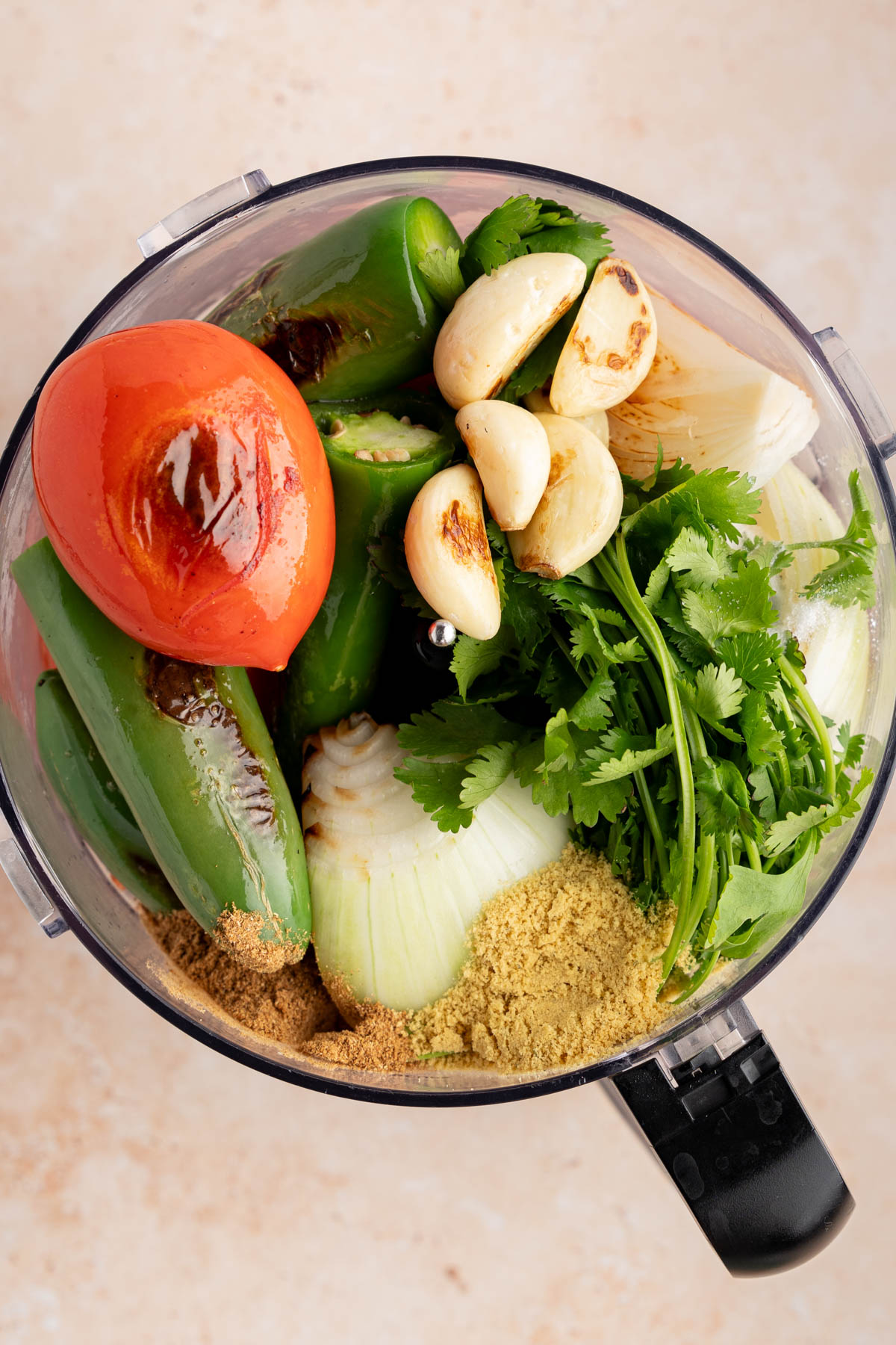 All of the ingredients for the salsa in a food processor, including the charred ingredients.