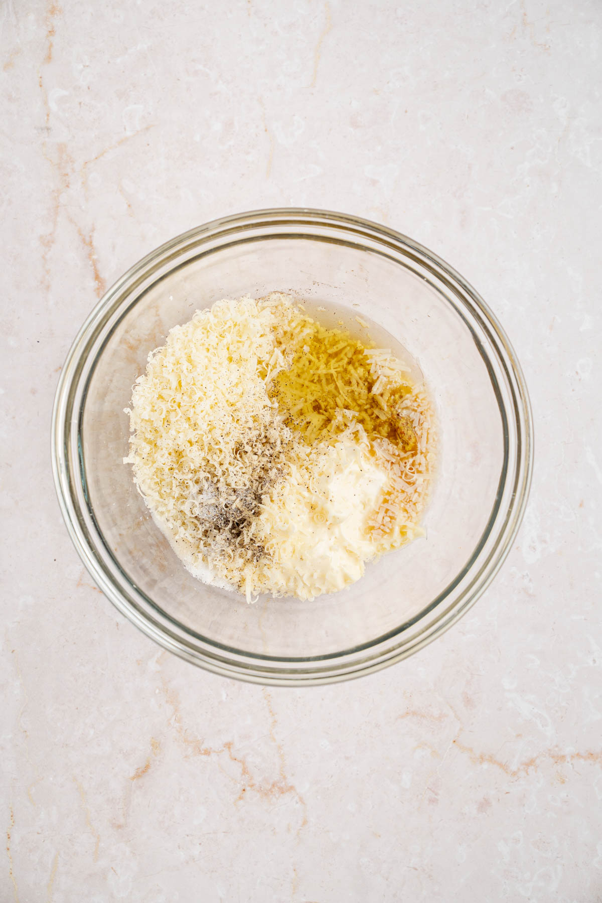 All of the ingredients for the Caesar dressing in a large glass bowl on a countertop.